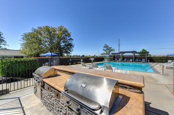 Bbq picnic area with grills and view of lounge chairs and pool 